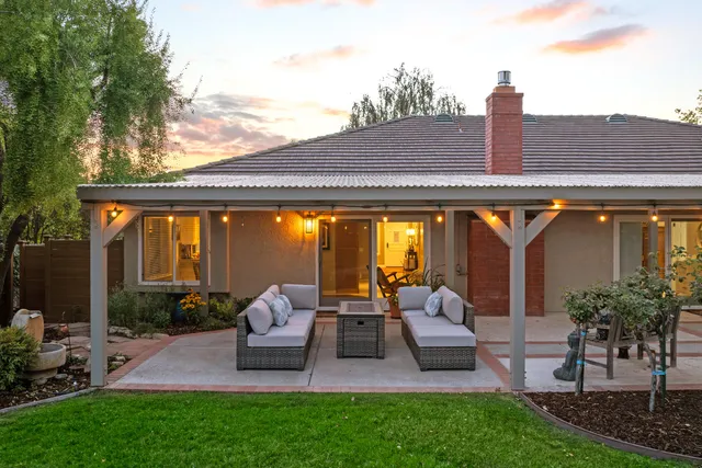 a view of patio with couches and a table and chairs with plants and garden
