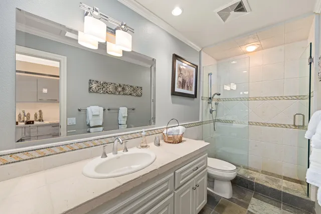 a bathroom with a granite countertop sink mirror vanity and toilet