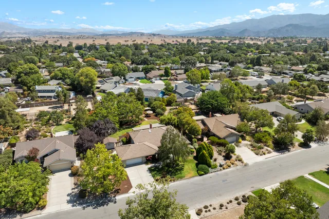 an aerial view of residential houses with outdoor space and trees