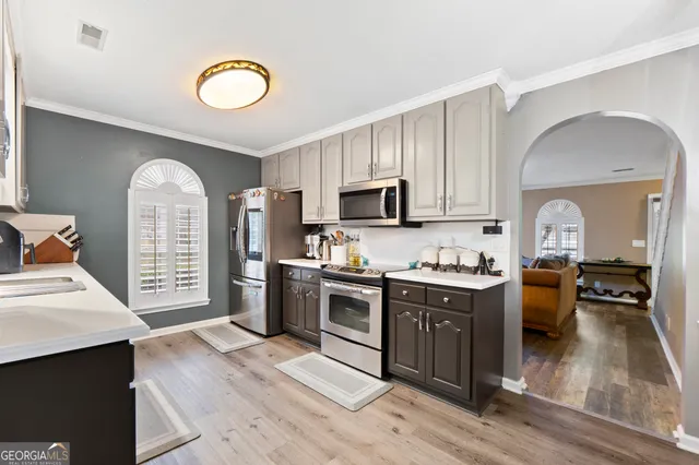 a kitchen with stainless steel appliances granite countertop a stove top oven a sink dishwasher and white cabinets with wooden floor