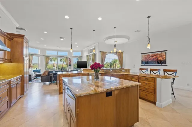 a kitchen with stainless steel appliances kitchen island granite countertop a dining table chairs and a refrigerator