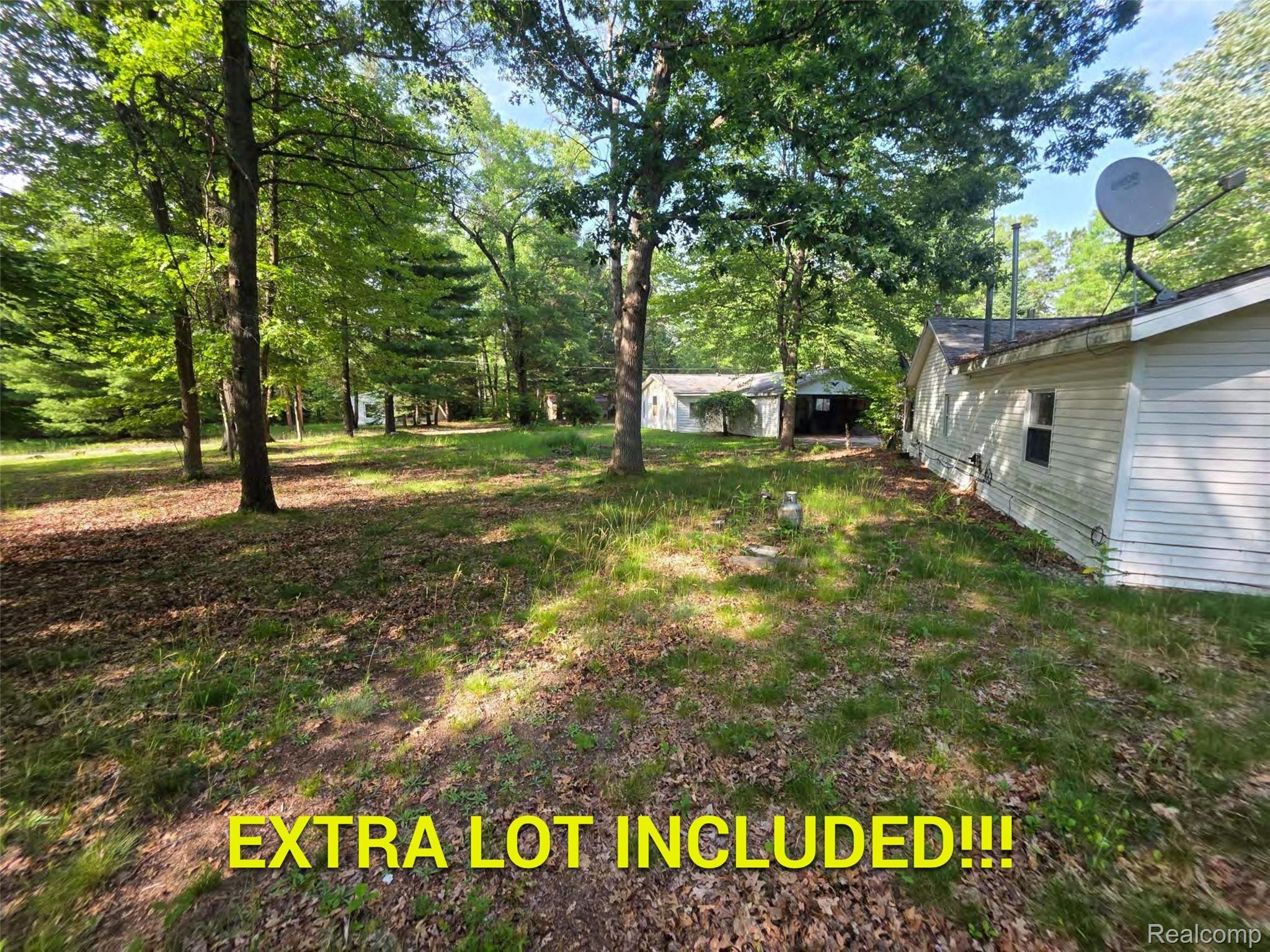 5420 Randy Drive Prescott, MI 48756 - Photo 6 of 31 Expansive wooded property featuring a white-sided structure with a satellite dish, an additional structure with a covered porch, and mature trees