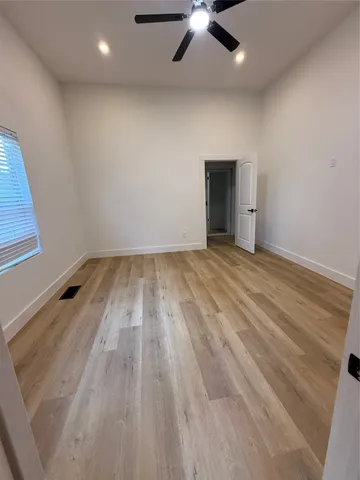 an empty room with wooden floor chandelier fan and windows