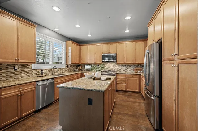 a kitchen with stainless steel appliances granite countertop a sink stove refrigerator and cabinets