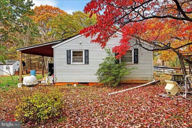 a backyard of a house with table and chairs under an umbrella