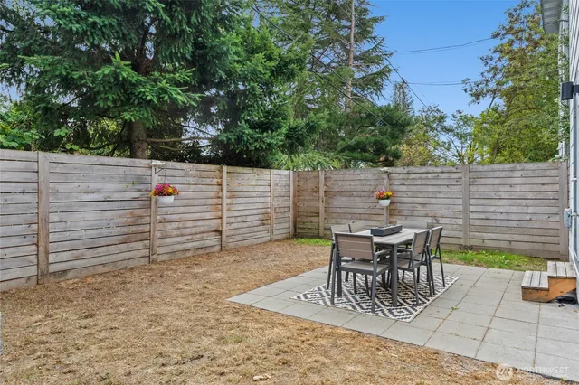 a view of a patio with table and chairs with wooden fence and plants