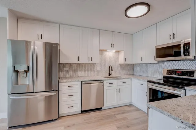 a kitchen with white cabinets and stainless steel appliances