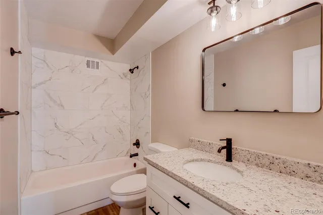 a bathroom with a granite countertop sink toilet and shower
