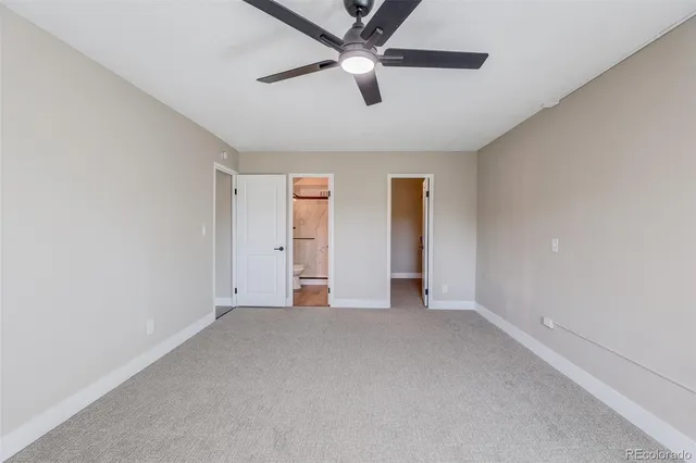 an empty room with chandelier fan and windows