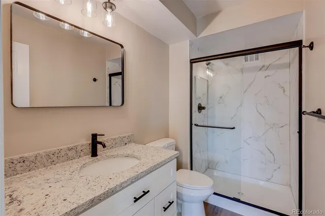 a bathroom with a granite countertop sink toilet and shower