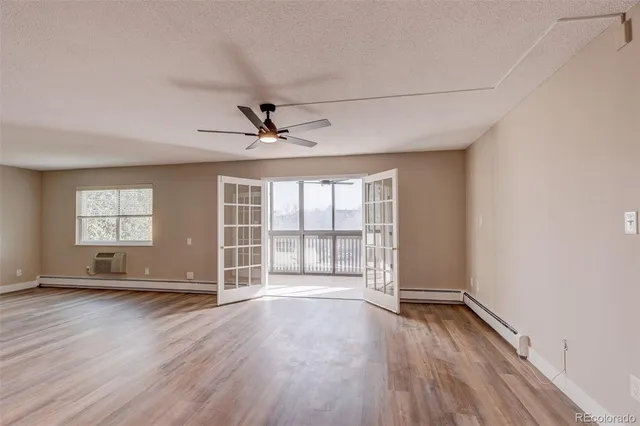 an empty room with wooden floor and windows