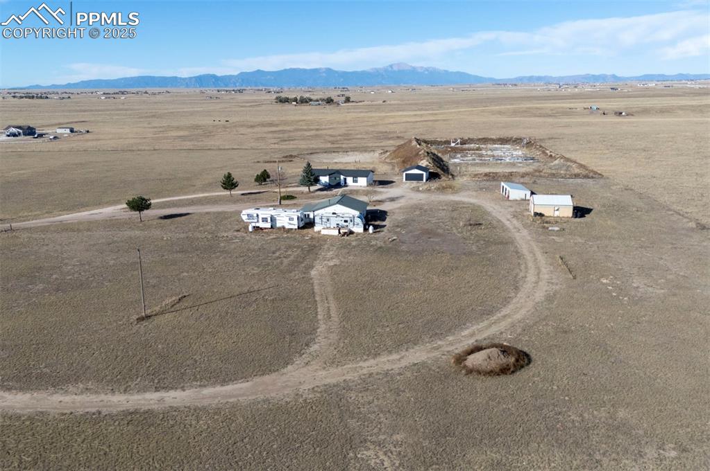 Aerial view of property and surrounding area featuring rural landscape and a mountain backdrop