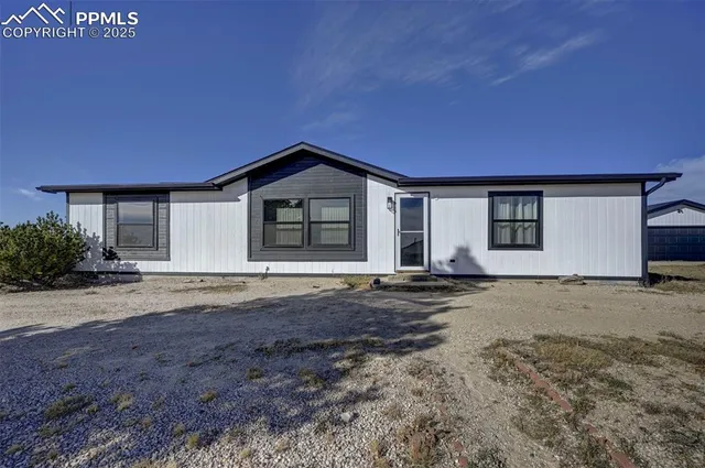 a front view of a house with a dirt road and a window