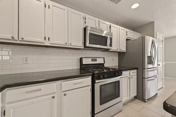 a kitchen with stainless steel appliances granite countertop white cabinets a stove a microwave and a refrigerator