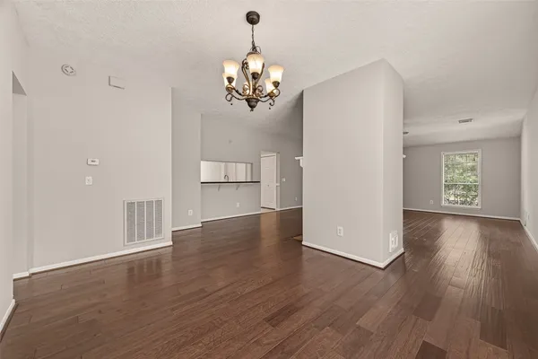 a view of a room with wooden floor chandelier and windows