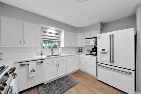 a kitchen with white cabinets and white appliances