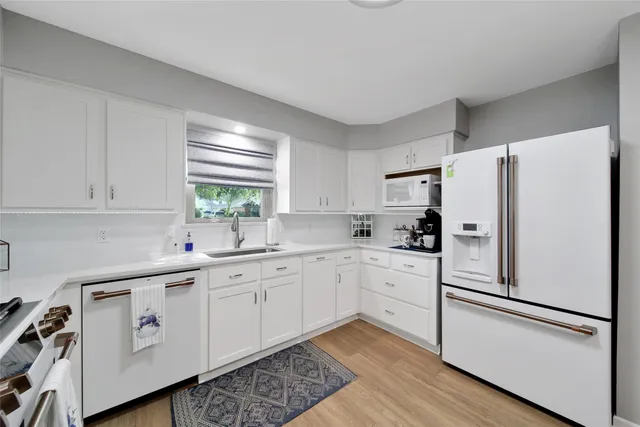 a kitchen with white cabinets and white appliances