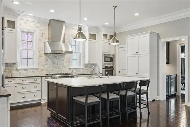 a kitchen with stainless steel appliances kitchen island granite countertop a table chairs sink and cabinets