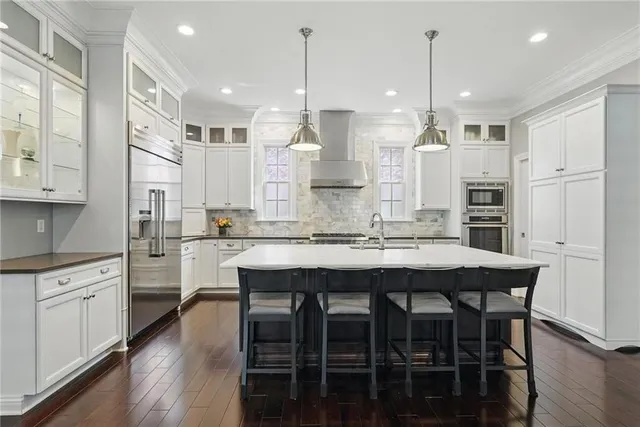 a kitchen with stainless steel appliances granite countertop a kitchen island hardwood floor and a sink