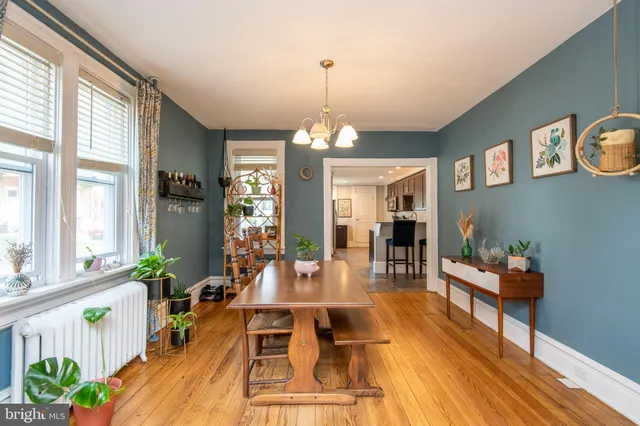 a dining room with wooden floor a chandelier a glass table and windows