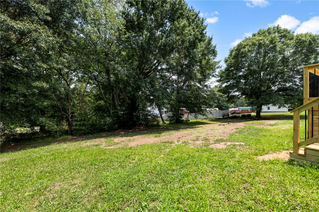 418 Old River Road Pelzer, SC 29669 - Photo 26 of 29 Green grounds stretch towards a tree-lined perimeter under a vibrant sky.
