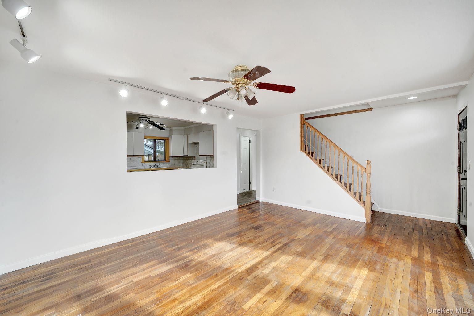 450 Rhodes Lane West Hempstead, NY 11552 - Photo 10 of 16 Open main living area with hardwood floors and staircase access.