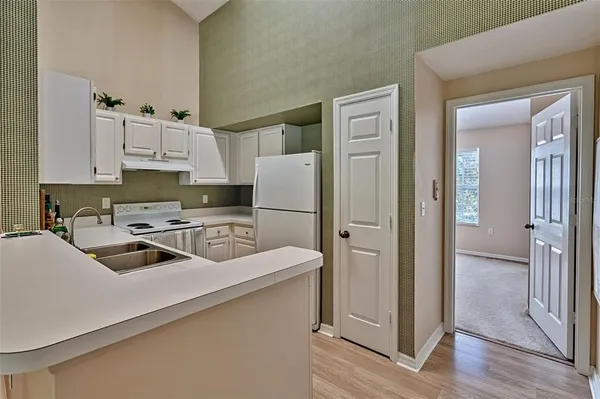 a kitchen with a refrigerator a sink and white cabinets