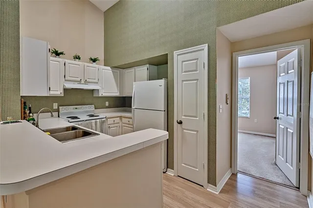 a kitchen with a refrigerator a sink and white cabinets