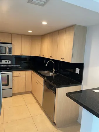 a kitchen with granite countertop a stove a sink a microwave and cabinets