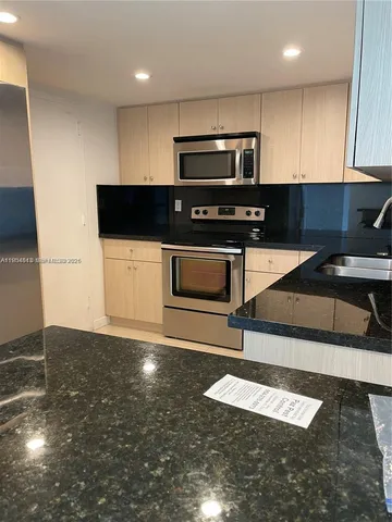 a kitchen with granite countertop a stove a sink a microwave and cabinets
