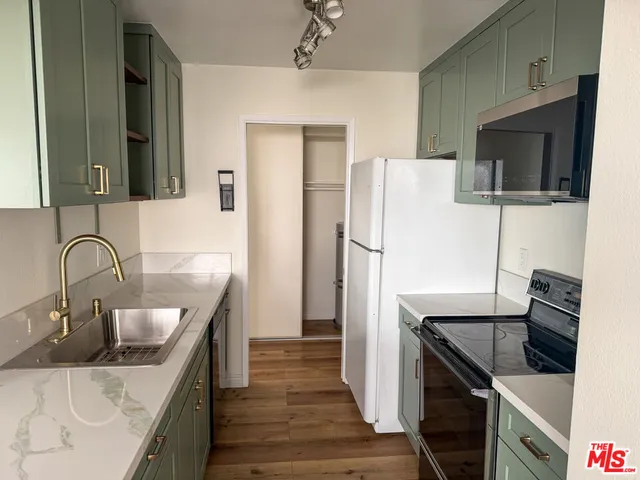 a kitchen with stainless steel appliances kitchen island a refrigerator sink and wooden cabinets