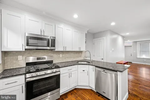 a kitchen with stainless steel appliances granite countertop a sink dishwasher a stove and a microwave oven with cabinets
