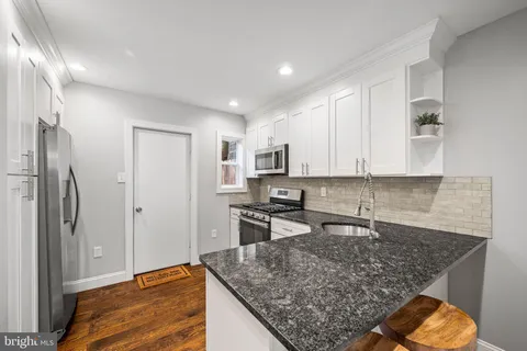 a kitchen with stainless steel appliances granite countertop a sink refrigerator and cabinets