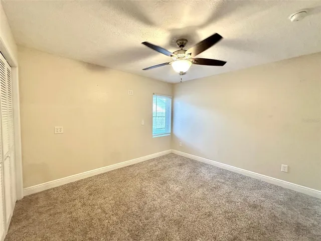 an empty room with a window and a fan