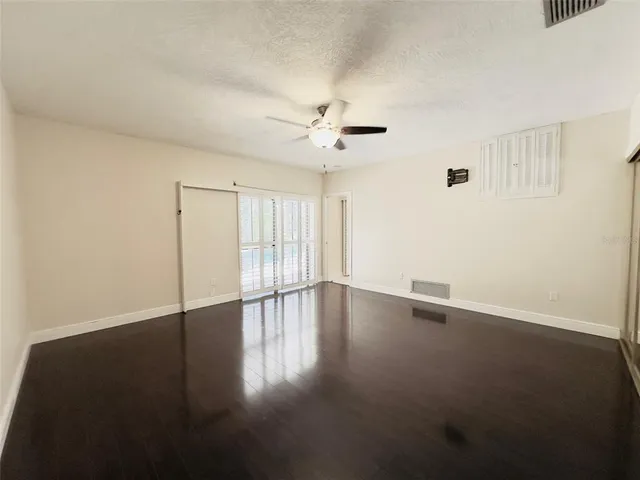 an empty room with wooden floor and windows