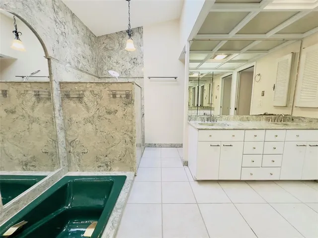 a bathroom with a granite countertop sink a mirror and shower