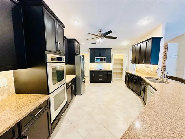 a large kitchen with stainless steel appliances kitchen island granite countertop a refrigerator and a stove top oven