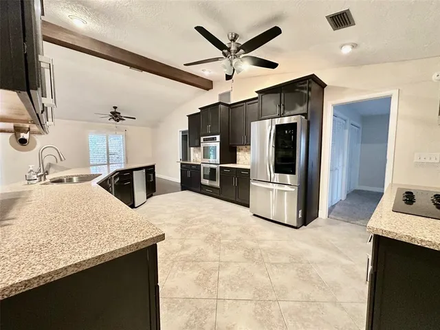 a kitchen with stainless steel appliances granite countertop a sink and a refrigerator