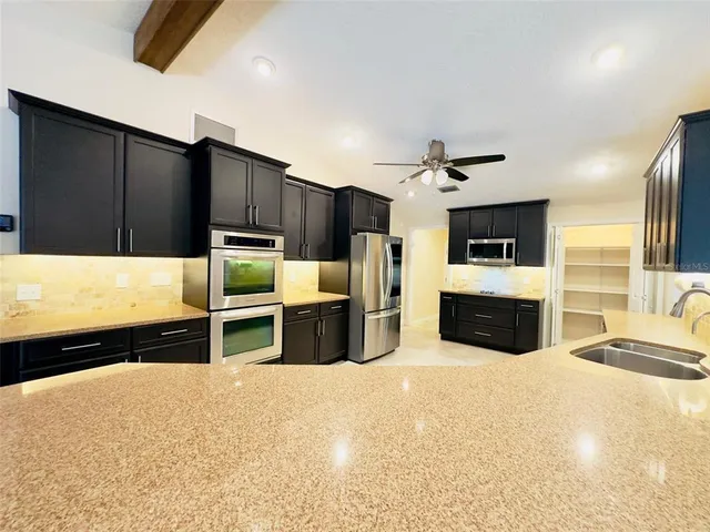 a kitchen with stainless steel appliances kitchen island granite countertop a refrigerator oven a sink and dishwasher