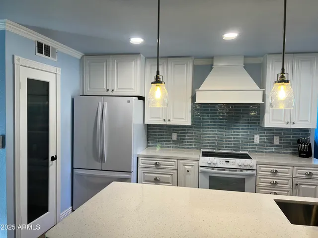 a kitchen with stainless steel appliances kitchen island a refrigerator sink and cabinets
