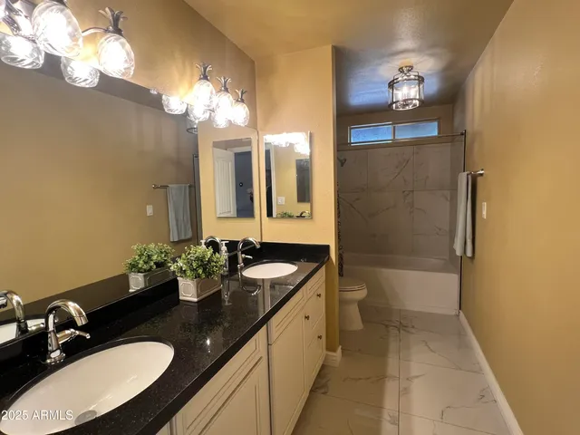 a bathroom with a granite countertop sink a toilet a mirror and shower