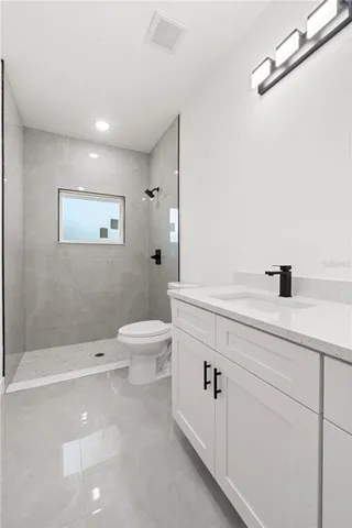 a bathroom with a toilet a sink a mirror and shower