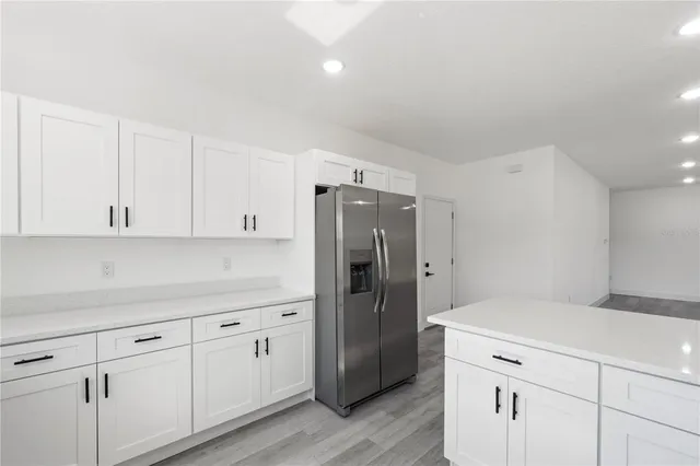 a kitchen with white cabinets and refrigerator