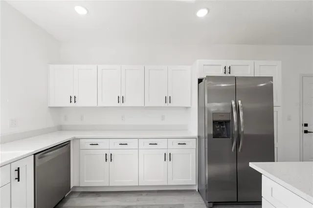 a kitchen with white cabinets and refrigerator