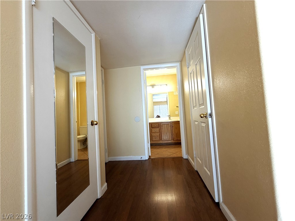 4955 South Lindell Road, Unit 203 Las Vegas, NV 89118 - Photo 16 of 31 A well-maintained hallway with warm-toned walls and classic hardwood flooring.