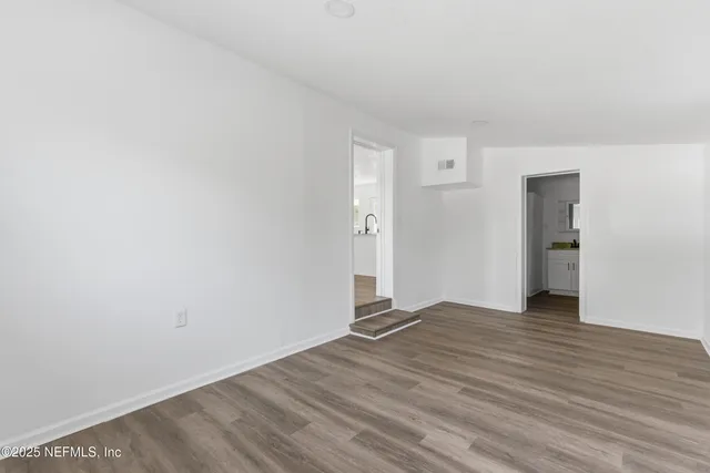 an empty room with wooden floor and window