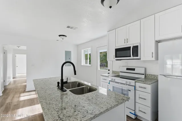 a view of a kitchen with wooden floor and electronic appliances