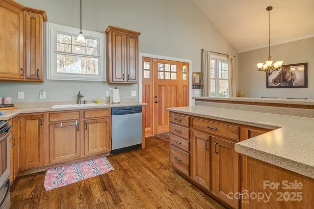 a kitchen with stainless steel appliances granite countertop a sink a stove cabinets counter space and windows