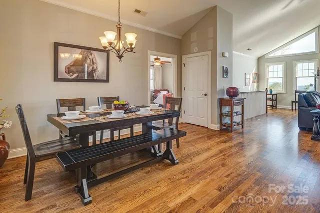 a dining room with wooden floor a chandelier a glass table and chairs