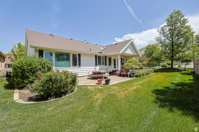 31 Village Square Road Centerville, UT 84014 - Photo 24 of 29 Expansive rear yard featuring a covered patio, a manicured lawn, established landscaping, and mature trees